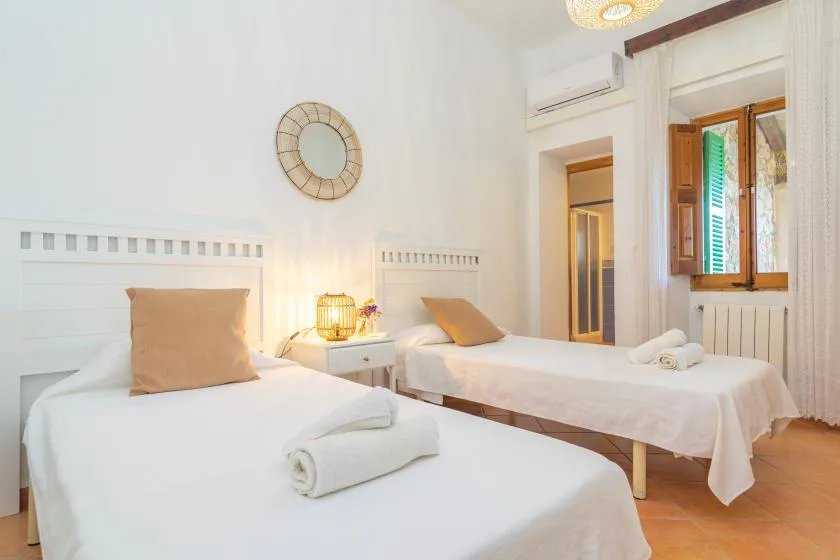 A bright bedroom with two single beds and a small bedside table.