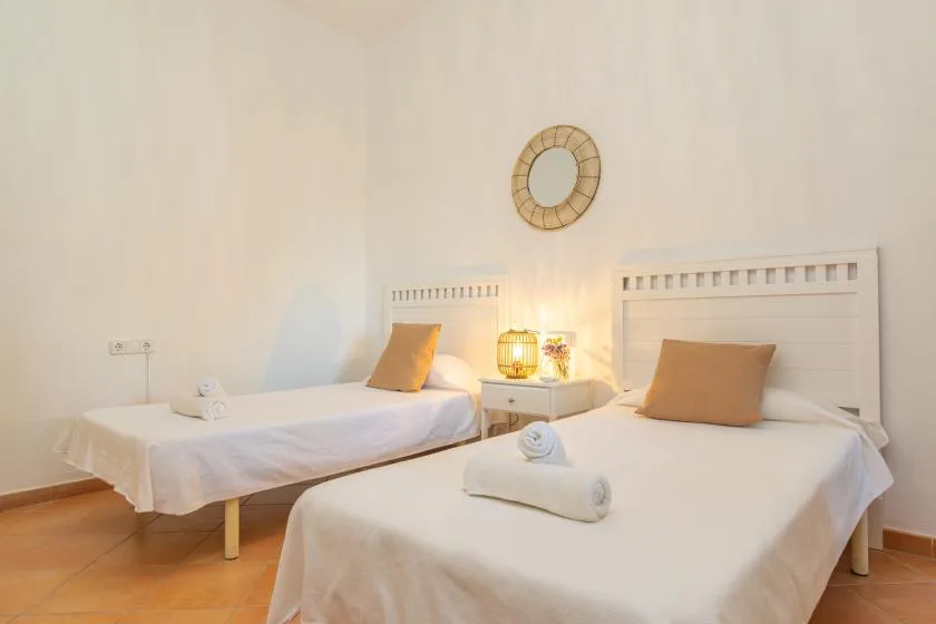 A bright bedroom with two beds and a small table between them.