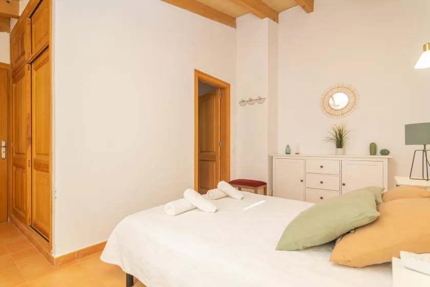 A bedroom with a neatly made bed and a dresser against the wall.