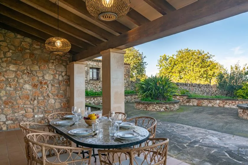 A covered outdoor dining area with a set table beside a stone courtyard.