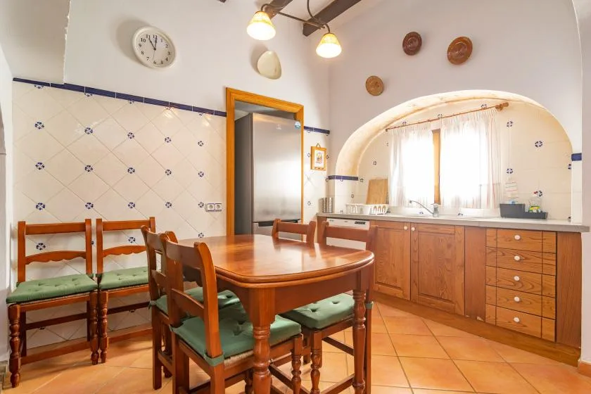 A tiled kitchen and dining area with wooden cabinets and a table surrounded by chairs.