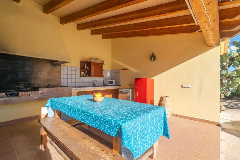 A rustic kitchen and dining area with a tiled table and exposed wooden beams.