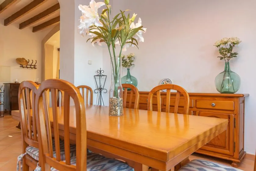 A wooden dining table and chairs sit beneath exposed ceiling beams.