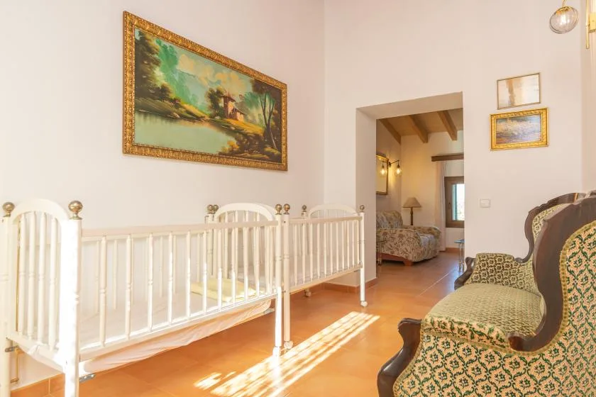 A bright bedroom with a white crib, patterned seating, and framed artwork.