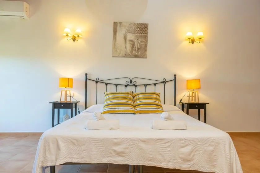 A bedroom with a neatly made bed and striped pillows beneath a wall picture.