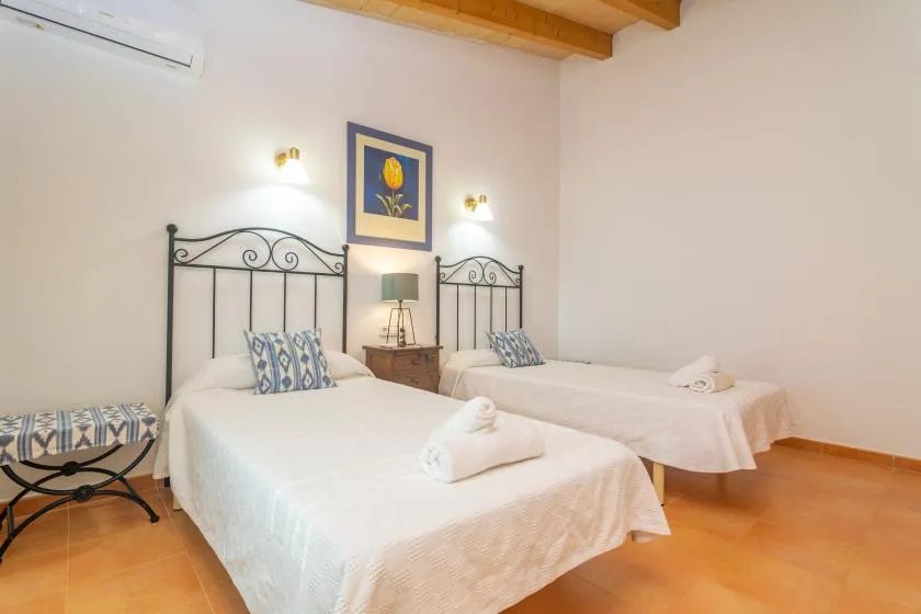 A bedroom with two beds and framed floral artwork on the wall.
