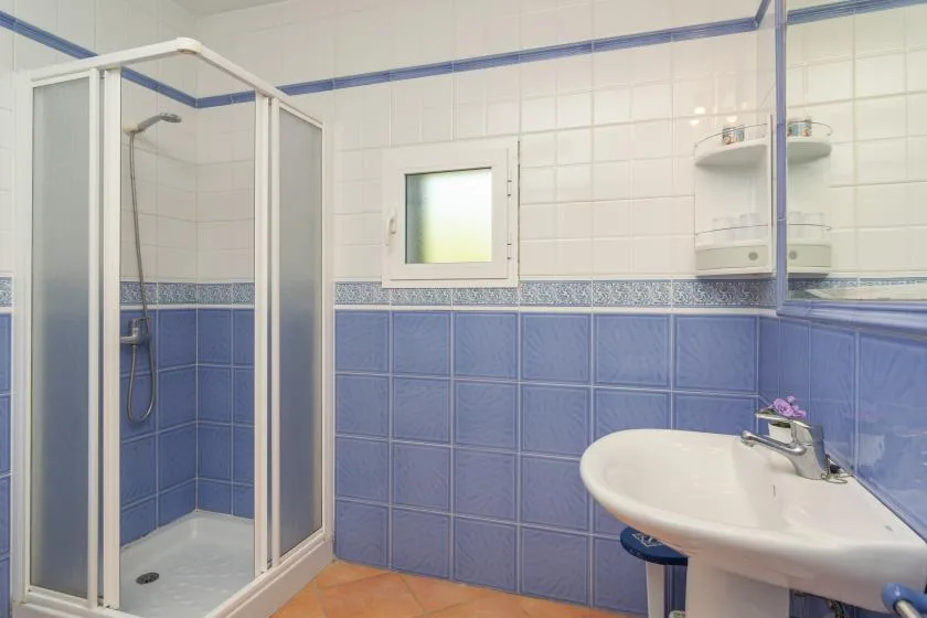 A tiled bathroom with a glass shower and a sink.