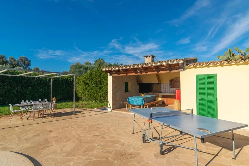 A sunny patio with a table-tennis table and outdoor dining area beside a house.