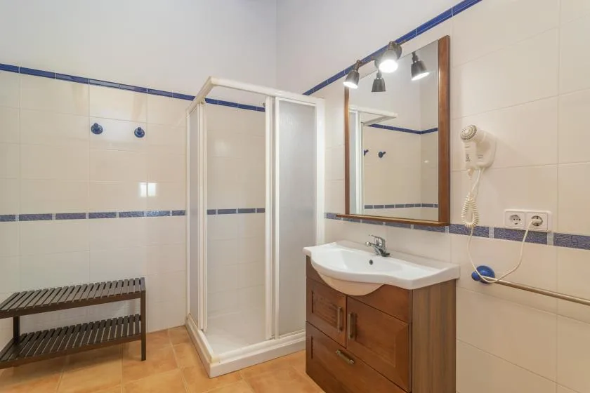 A tiled bathroom with a glass shower, sink, and wall mirror.