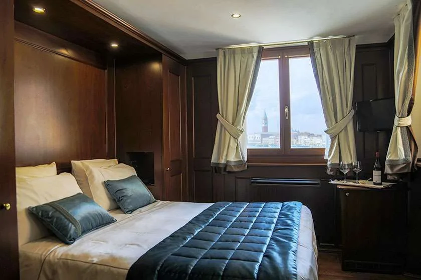 Dormitorio con cama, paredes de madera y una ventana con vistas a la ciudad.
