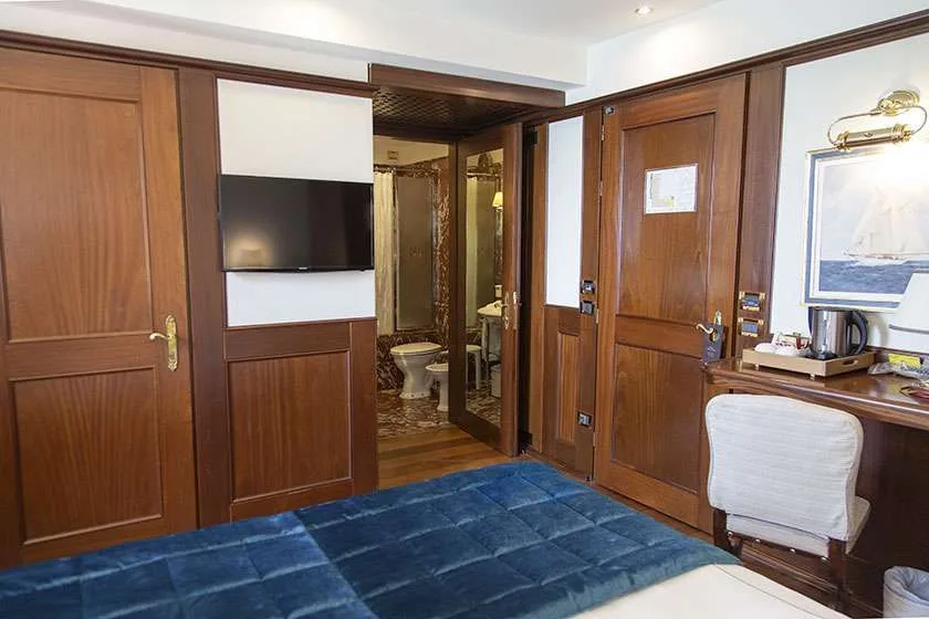 Habitación de hotel con cama, televisor de pared, escritorio y puerta del baño abierta.