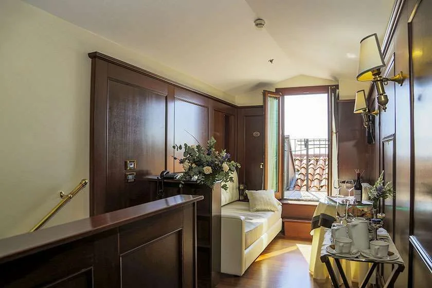 Pasillo de hotel revestido de madera con sofá y ventana.