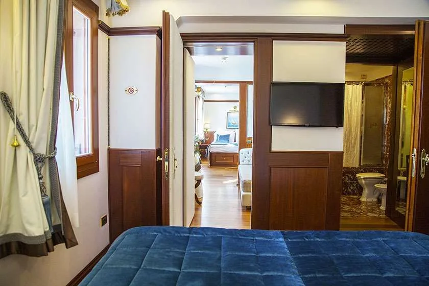 Vista desde una cama a través de una puerta hacia otra habitación y un baño.