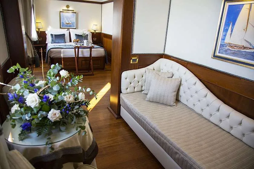 Suite de hotel con cama, sofá y mesa de cristal con flores.