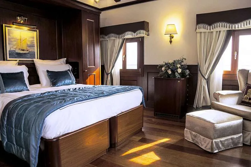 Dormitorio con cama, detalles de madera, ventanas y un sillón.