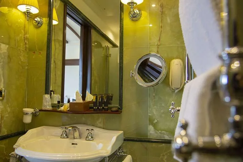 Lavabo de baño junto a paredes de mármol verde.