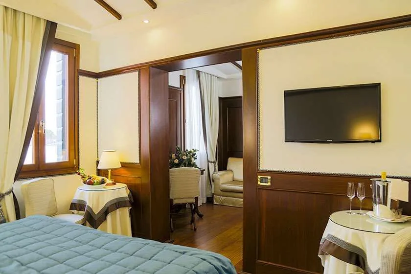 Dormitorio de hotel con cama, televisor de pared y mesa auxiliar.