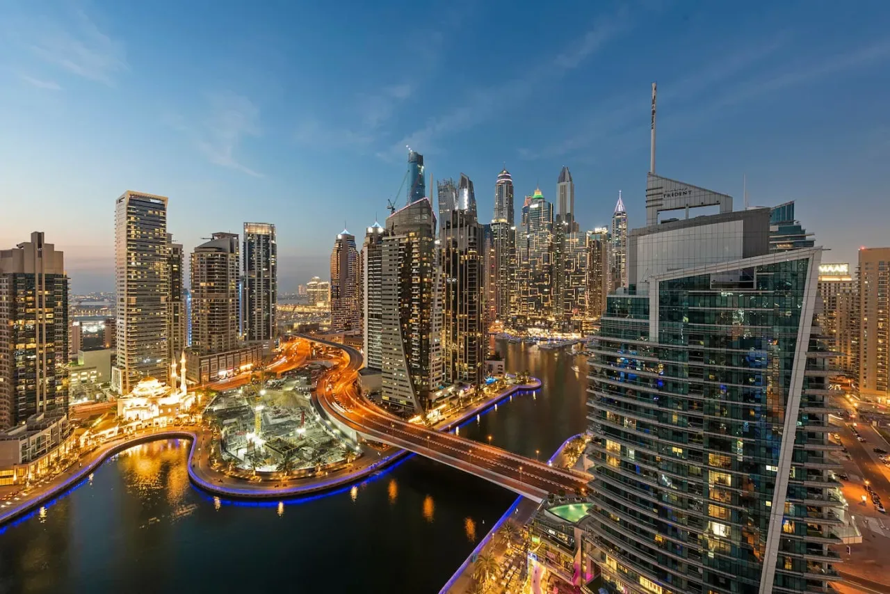Un horizonte urbano rodea un canal, con edificios y vías iluminados.