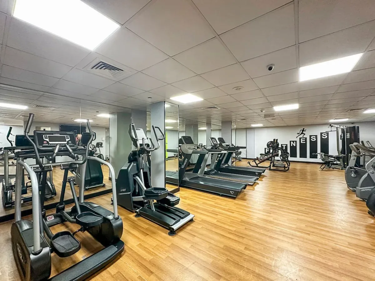 Un gimnasio con máquinas de ejercicio y suelo de madera.