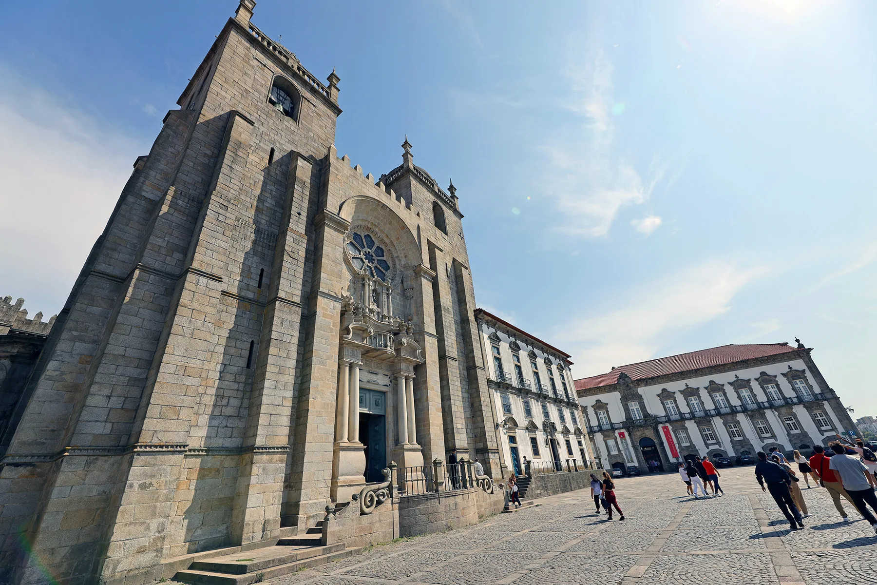 A large stone church faces a cobbled plaza lined with historic buildings.
