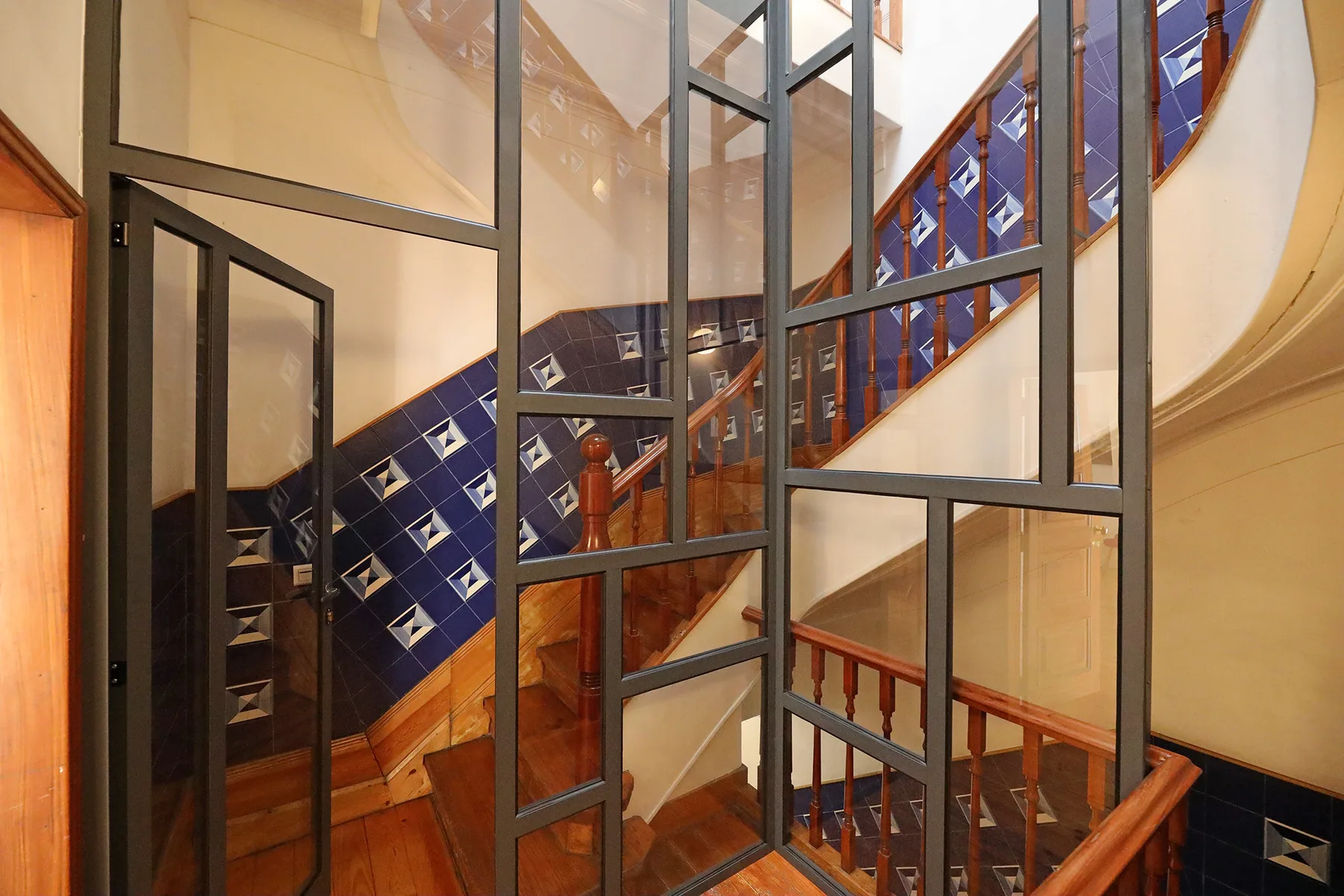 An interior staircase with wooden railings and blue patterned tiles.
