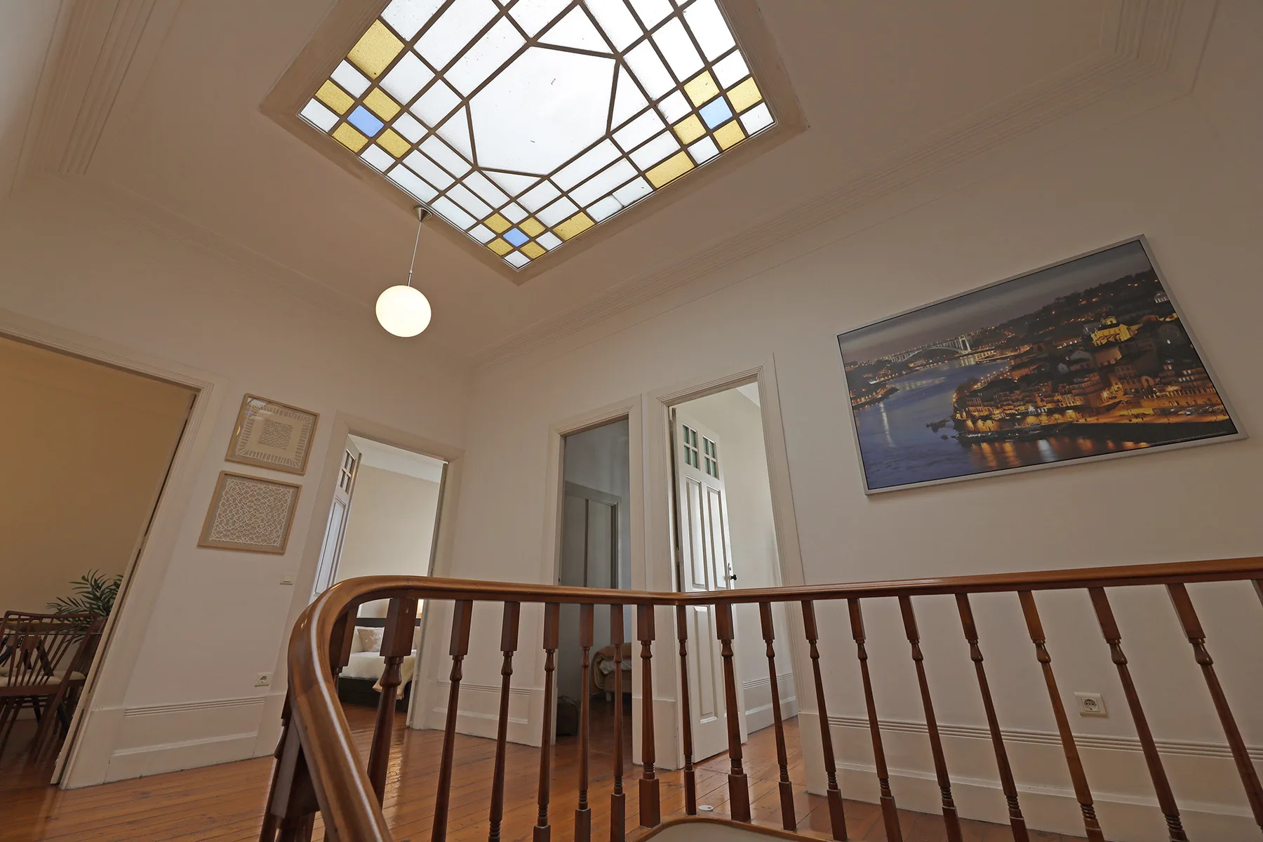 An interior hallway with a wooden railing and a decorative skylight.