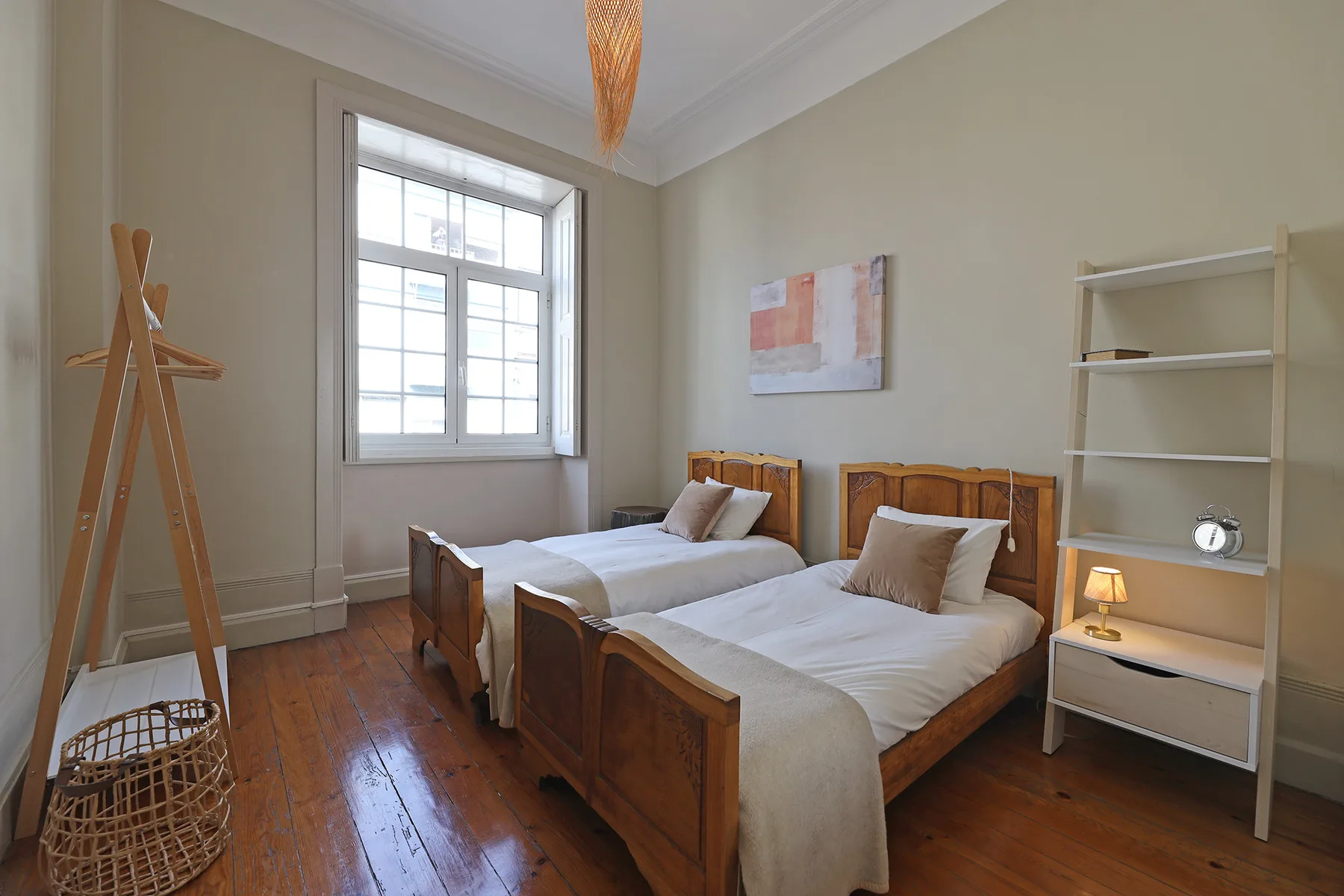 A bedroom with two beds, a large window, and a shelving unit.