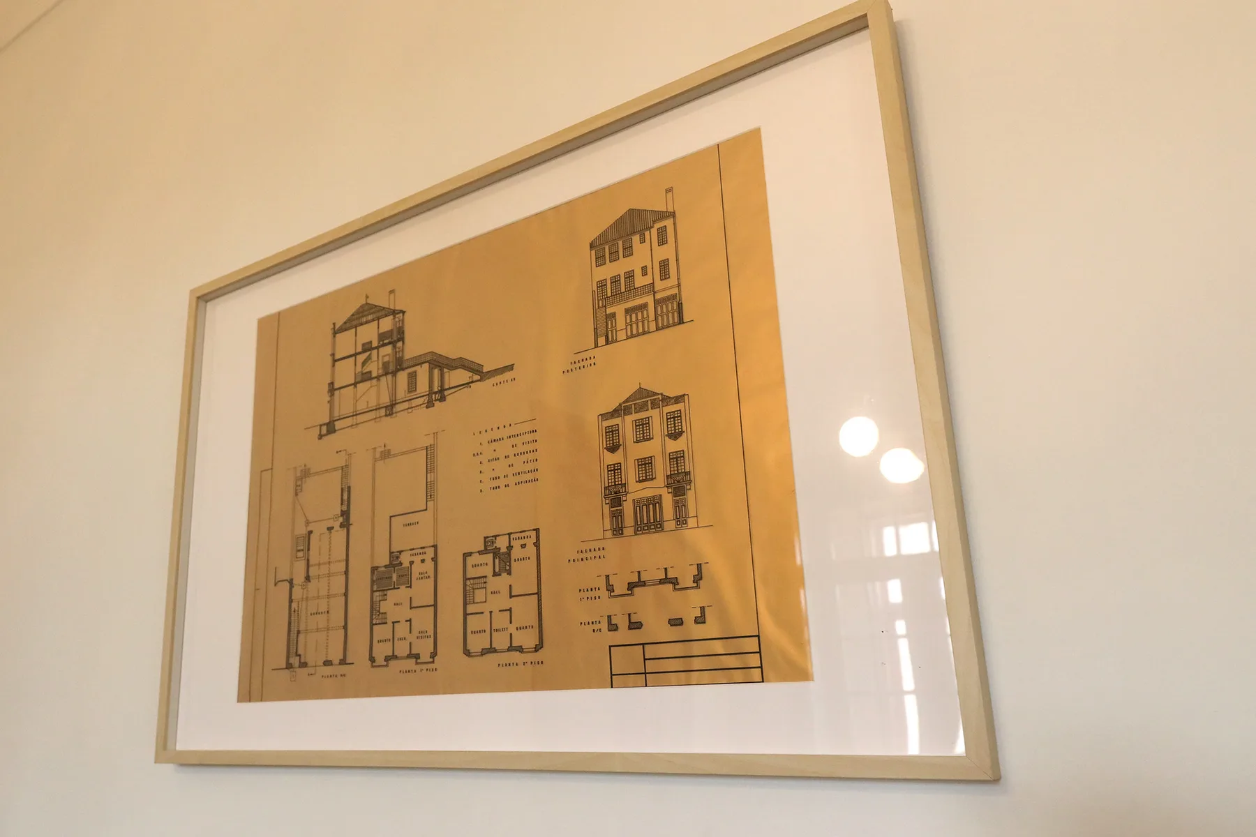 A framed architectural drawing hangs on a light-colored wall.