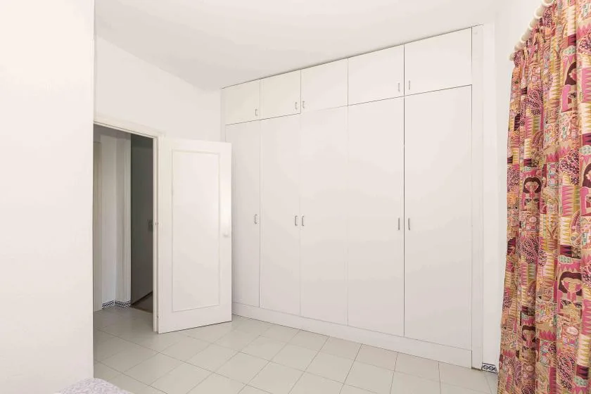 A bedroom with built-in wardrobes and a patterned curtain.