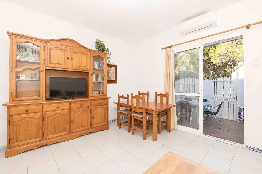 A bright dining area with a wooden table and cabinet beside a sliding glass door.