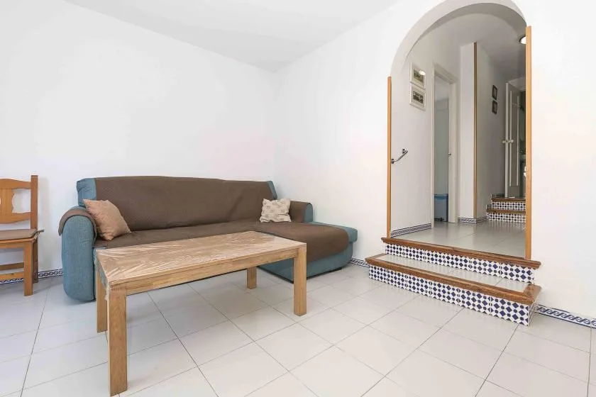 A living room with a sofa and a wooden coffee table beside an arched opening.
