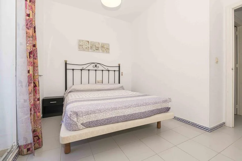 A bedroom with a bed, patterned bedding, and a small bedside table.