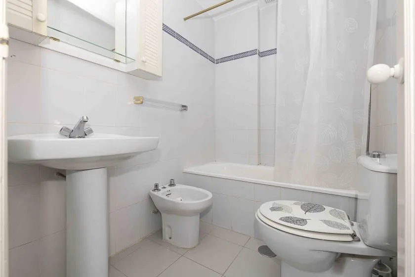 A tiled bathroom with a sink, toilet, and bathtub behind a shower curtain.
