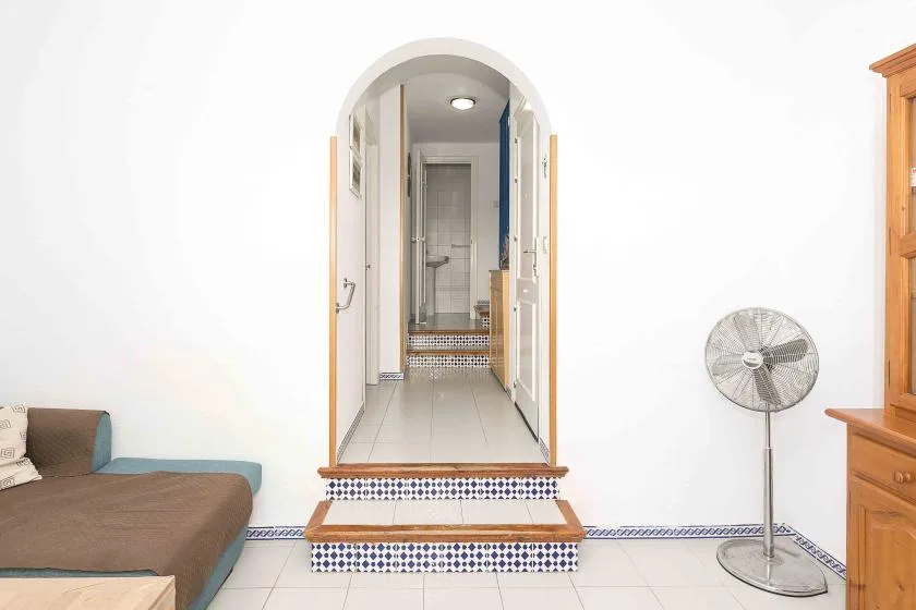 A tiled room with an arched doorway opening onto a narrow hallway.