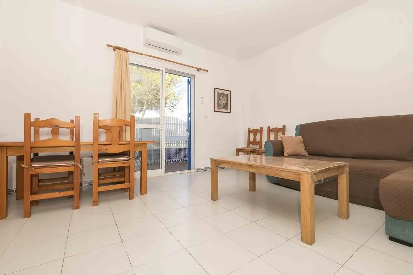 A living room with wooden seating, a low coffee table, and a sliding glass door.