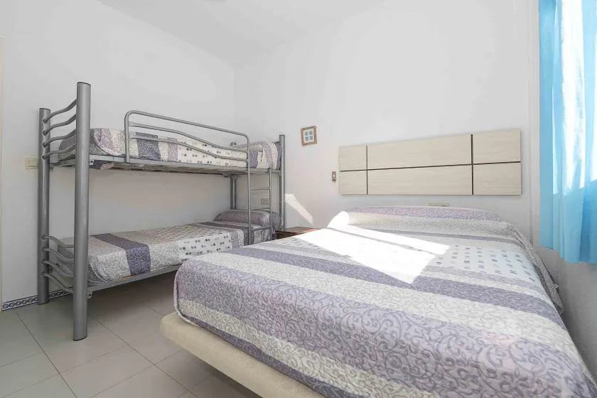A bedroom with a double bed and a metal bunk bed beside it.