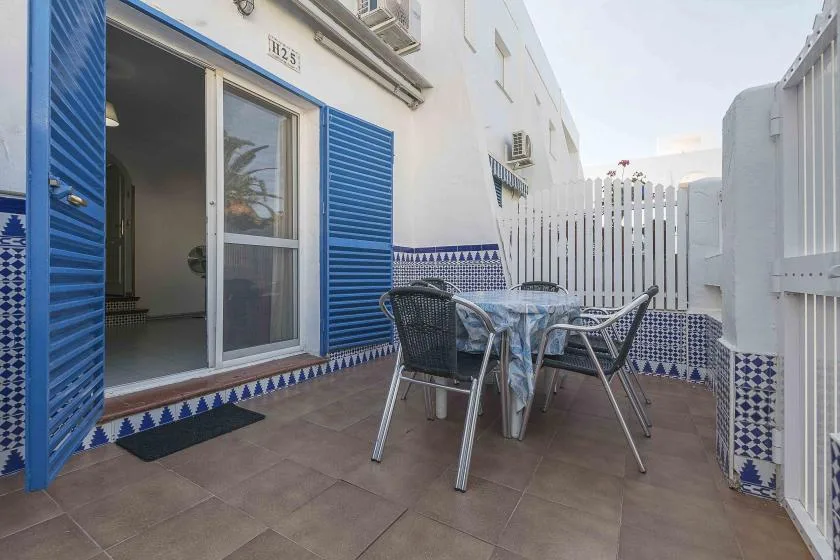A tiled outdoor dining area with a table and seating beside an open sliding door.