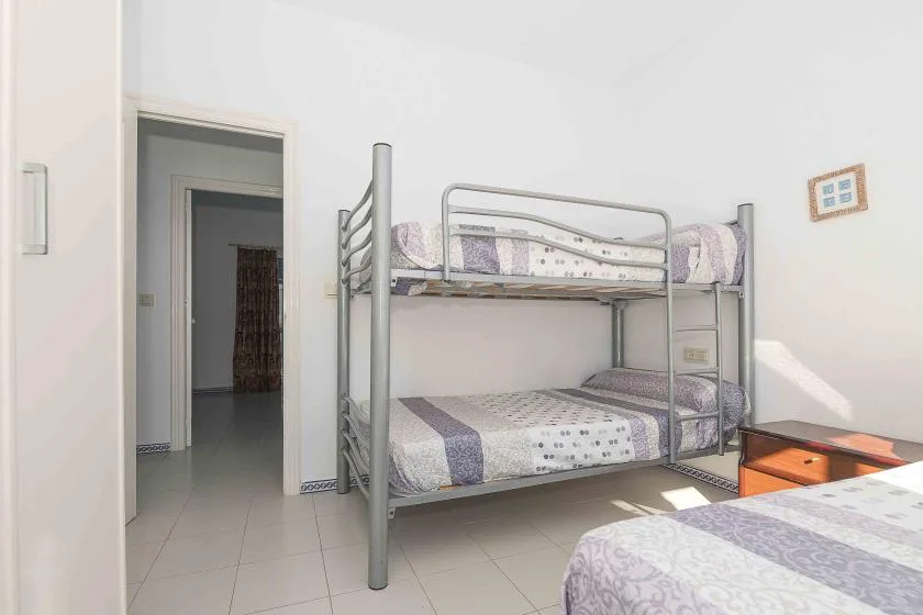 A bedroom with metal bunk beds and patterned bedding.