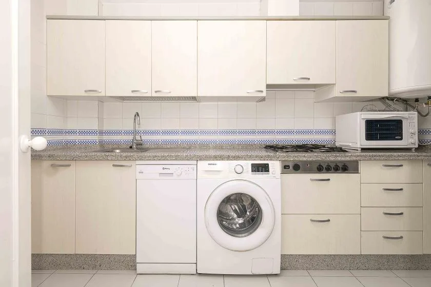 A kitchen with white cabinets, a washing machine, and countertop appliances.