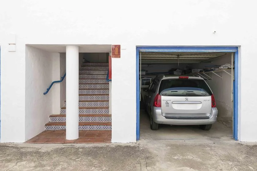 A building entrance beside an open garage with a parked car.