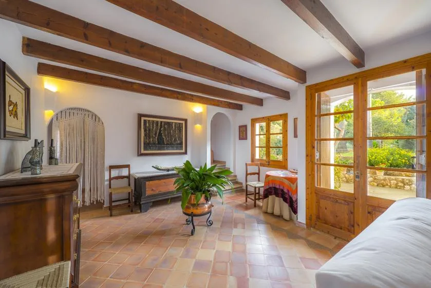 A bedroom with exposed wooden beams, a bed, and a small seating area.