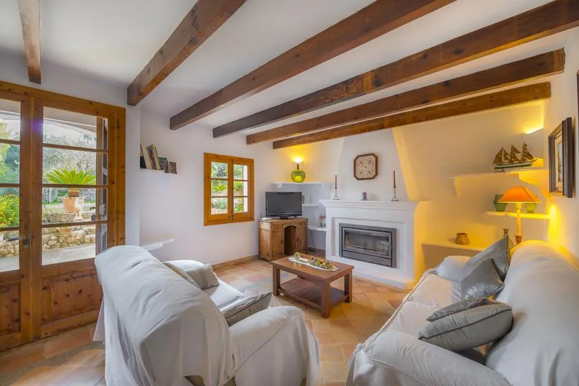 A bright living room with seating, a fireplace, and exposed ceiling beams.