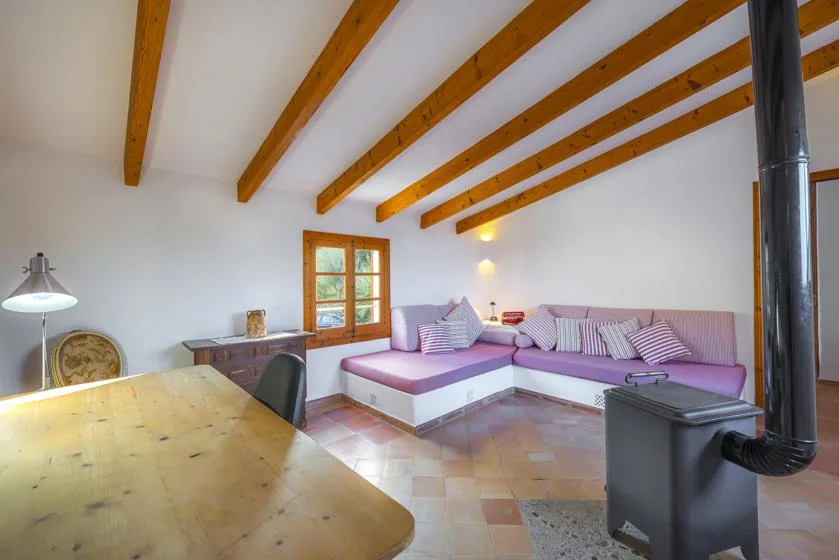 A living room with a corner seating area beneath exposed wooden ceiling beams.
