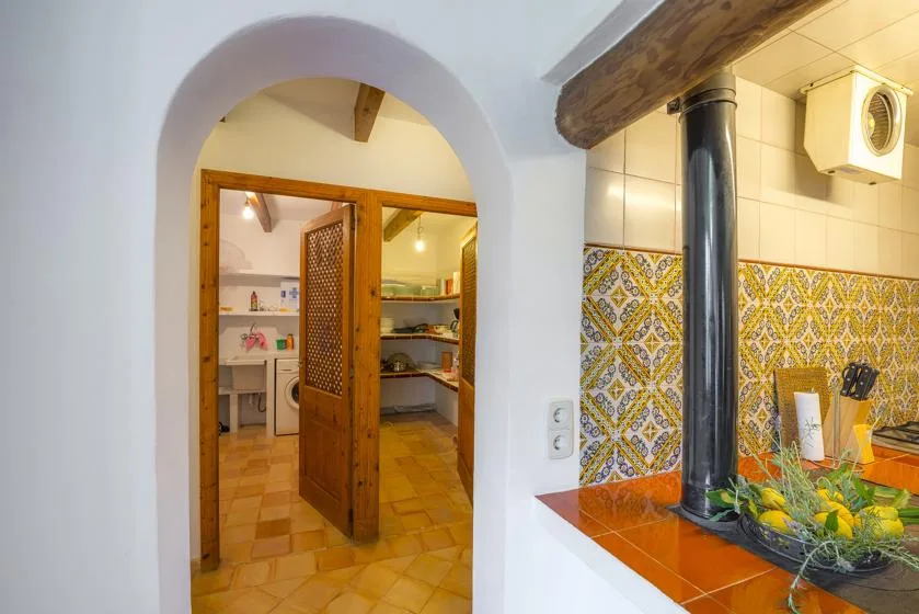 A tiled kitchen is visible through an arched doorway, with a counter in the foreground.