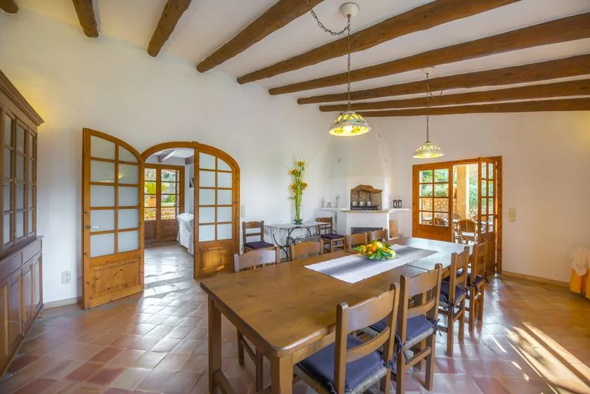 A dining room with a large wooden table beneath exposed ceiling beams.