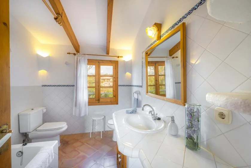 A bright bathroom with a sink, toilet, and window.