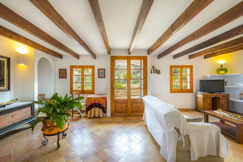 A bright living room with exposed wooden ceiling beams and a central glass door.