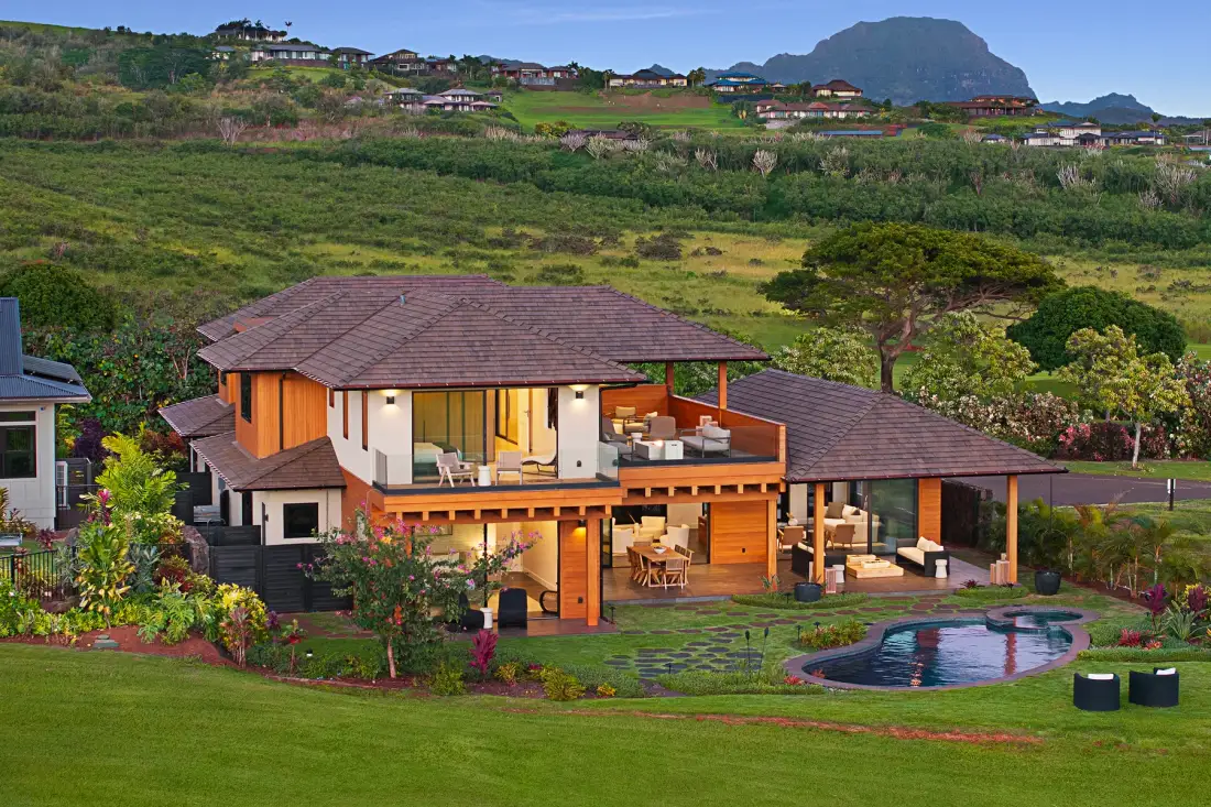Una casa moderna con césped ajardinado, patio y una pequeña piscina.