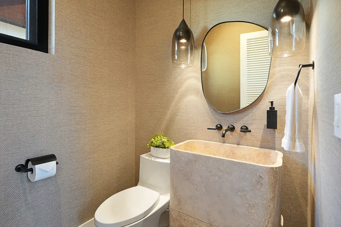 Un baño con lavabo, inodoro y espejo redondo.