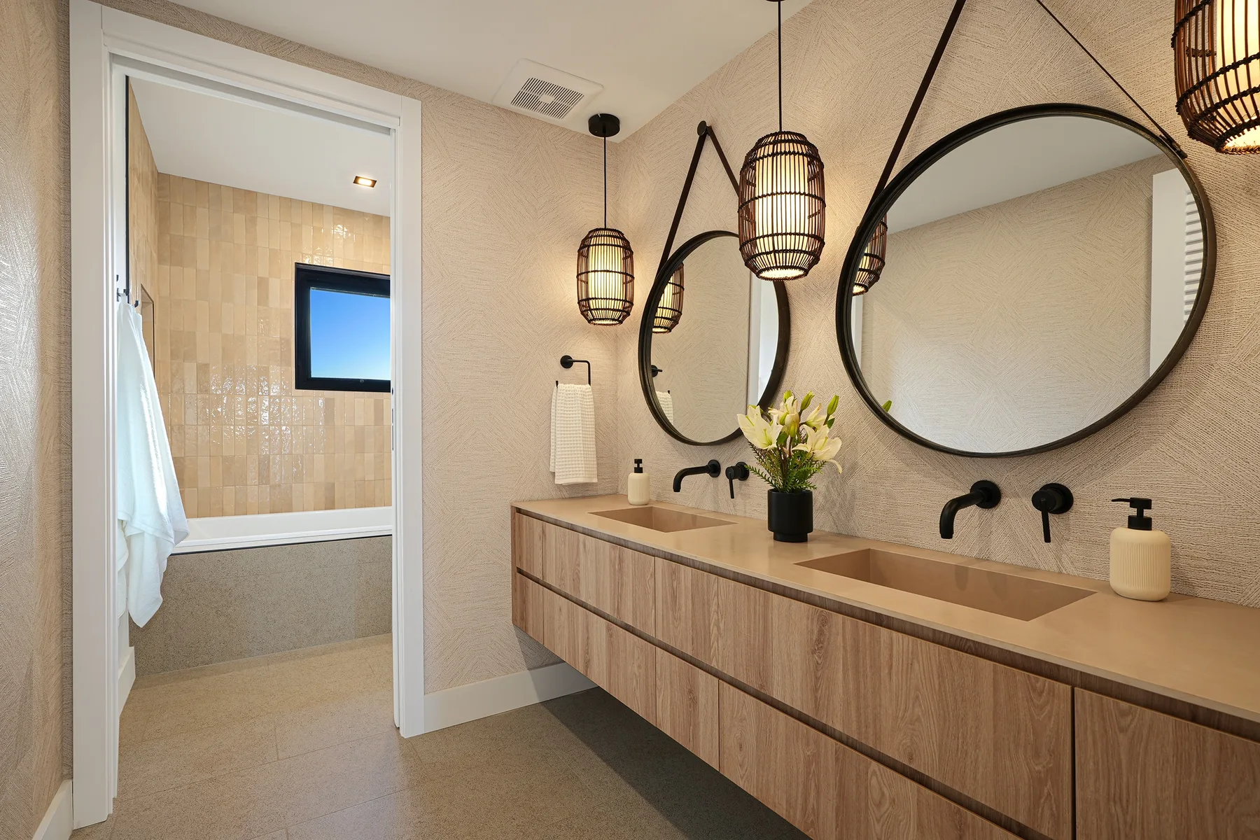 Un tocador de baño con dos lavabos, espejos redondos y luces colgantes.